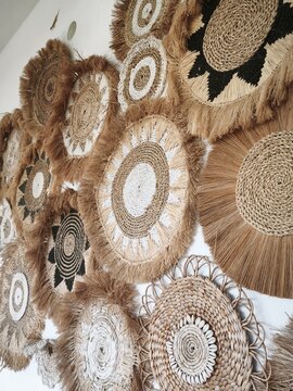 Boho rattan wall art decoration made from natural seagrass raffia and cowrie shells hanging on white wall