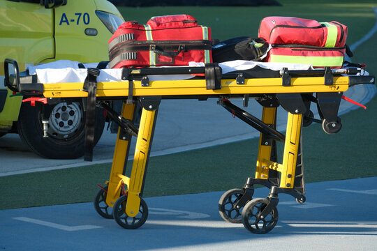 Emergency stretcher with medical bags beside an ambulance. Paramedic equipment for patient transport and urgent care. Ambulance service and emergency response. Healthcare and rescue