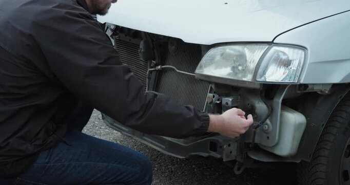 Man checking the exposed front of a damaged car for repair