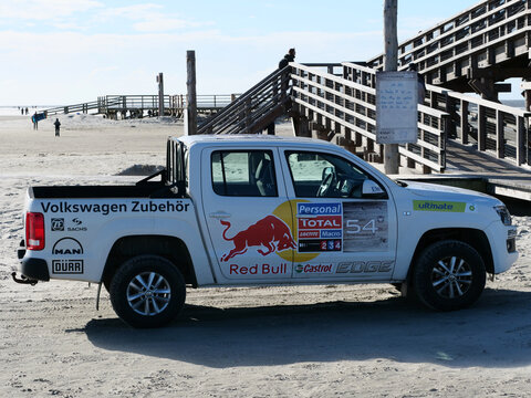Germany, St. Peter Ording, October 17. 2026, white Volkswagen Amarok pickup truck with various racing and sponsor decals including Red Bull, Castrol EDGE, Total, and Volkswagen Zubeh&ouml;r