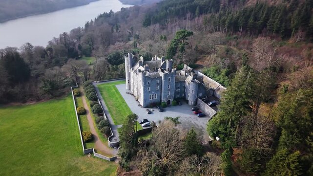 Aerial pull back from Castlewellan Castle and its terraced gardens with Castlewellan Lake beyond, County Down, Northern Ireland