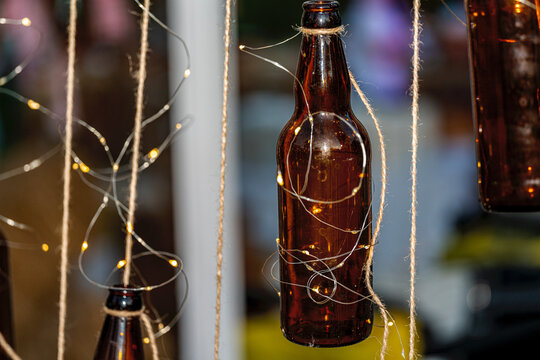 Oktoberfest celebration concept with beer bottles decorated with glowing small lights. Warm and cozy festive background for beer festival or pub party.
