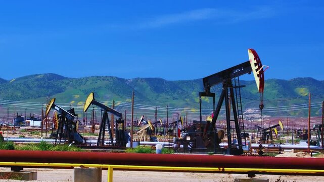 Oil Pumpjacks Extracting Crude Oil in Field with Mountain Background
