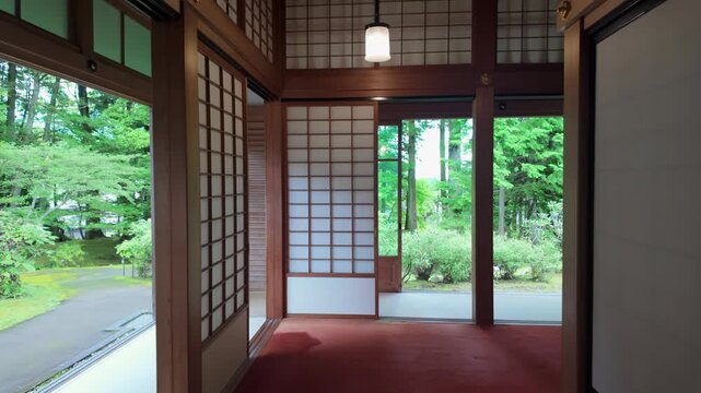 Traditional Japanese architecture interior with sliding shoji doors and red carpet leading to a lush green garden at Nikko Tamozawa Imperial Villa Memorial Park, Nikko, Japan.