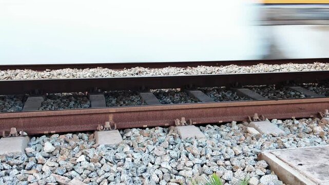 Fast commuter train wheels speeding along gravel railway tracks