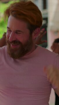 Energetic man dancing forward outdoors while diverse friends laugh in celebration