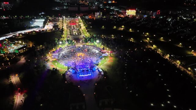 Aerial view of a huge crowd celebrating at a brightly lit night carnival square during the Torch Festival, Southwest China, D-Log lossless file format