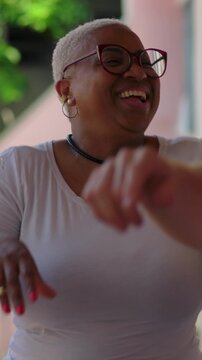 Joyful African American woman dancing playfully with friends outdoors at community party