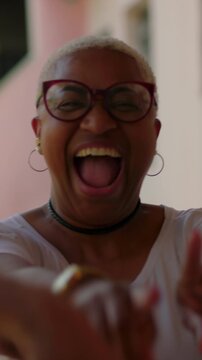 Playful African American female laughing while dancing with diverse friends in sunny garden