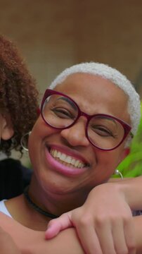 African American woman and teenage son smiling outdoors, camera pan family moment