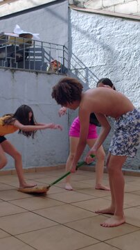 Carefree children playing homemade jumping game in backyard, authentic childhood