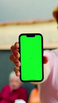 Hand holding smartphone with chroma key green screen and tracking markers outdoors