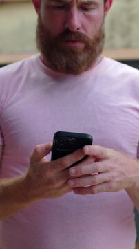 Serious man frowning while reading smartphone outdoors, focused on bad news