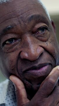 Thoughtful elderly African American man with hand on chin outdoors, contemplative senior headshot