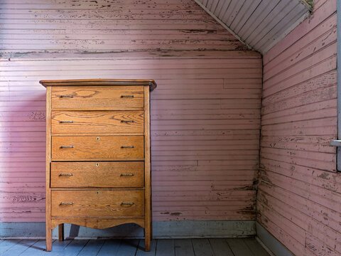 An antique wood dresser sits in a room with pink slatted walls