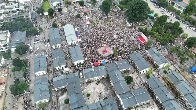 Aerial drone view of festival crowds filling the streets between rooftops during the Torch Festival, Southwest China, D-Log lossless file format