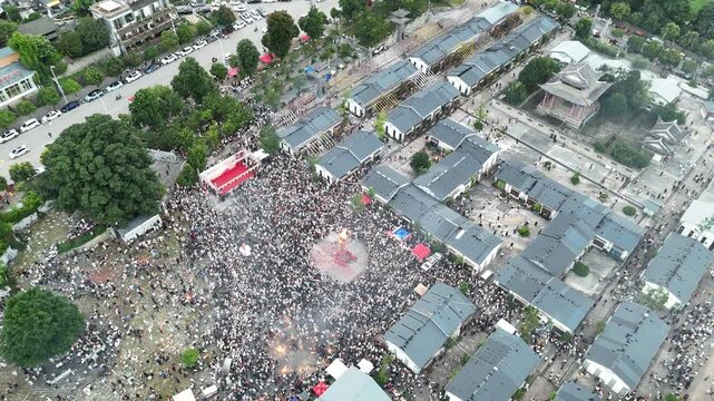 Aerial drone footage of a huge crowd gathering around the giant torch during the Torch Festival in a Chinese town, D-Log lossless file format