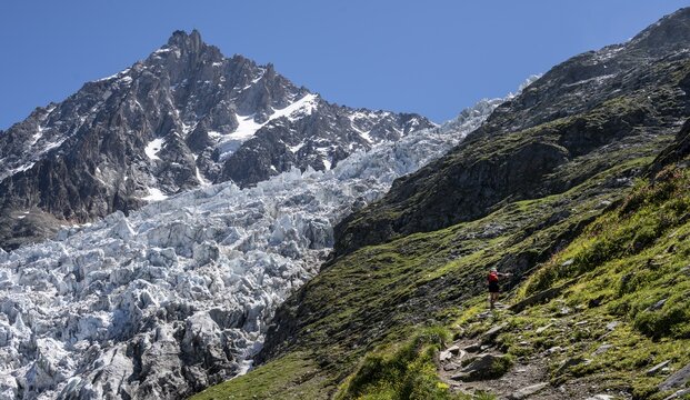Hiker on hiking trail, hiking trail La Jonction, glacier Glacier des Bossons, summit of Aiguille du Midi, Chamonix, Haute-Savoie, France