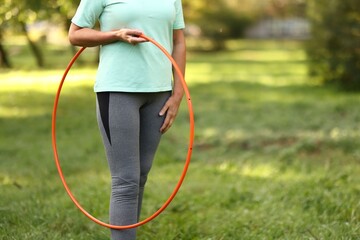 Senior woman with hula hoop in park, closeup. Space for text © New Africa