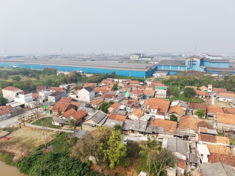 The image appears to show an aerial view of a densely populated residential area situated right next to an industrial zone specifically, the Achilles tire factory in Cikarang.