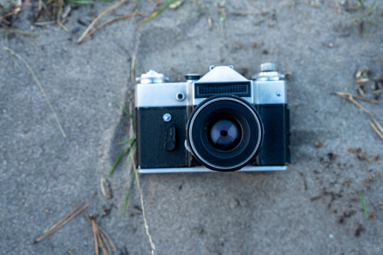 The camera is lying on the sand.
