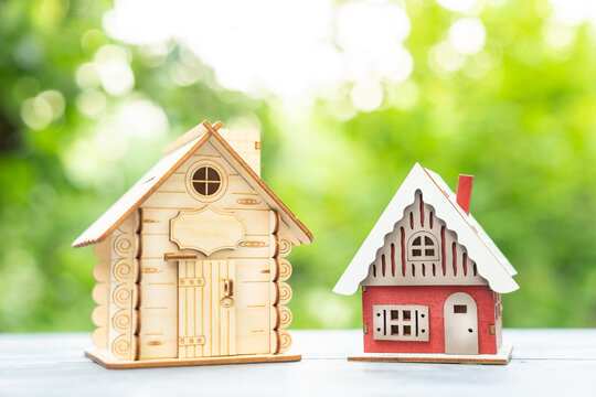 Two Toy Houses on a green background, foliage.