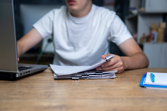 A man works with documents using a laptop