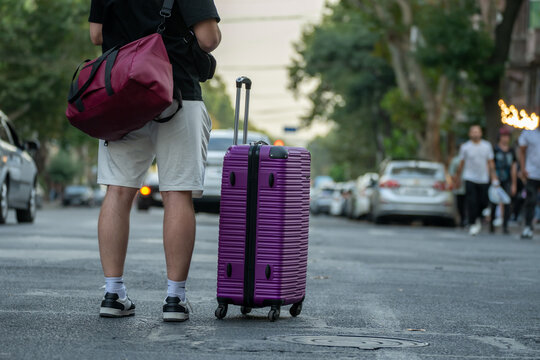A tourist with a suitcase on the street.