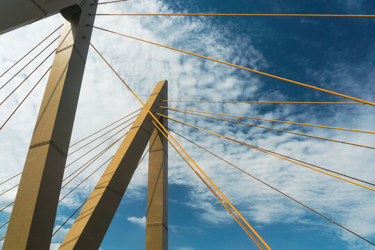 Low angle view of cable-stayed bridge with yellow cables against blue sky