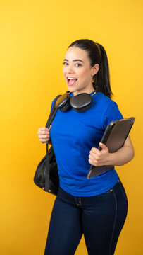 Young latina woman smiling while carrying a tablet and backpack with headphones for education