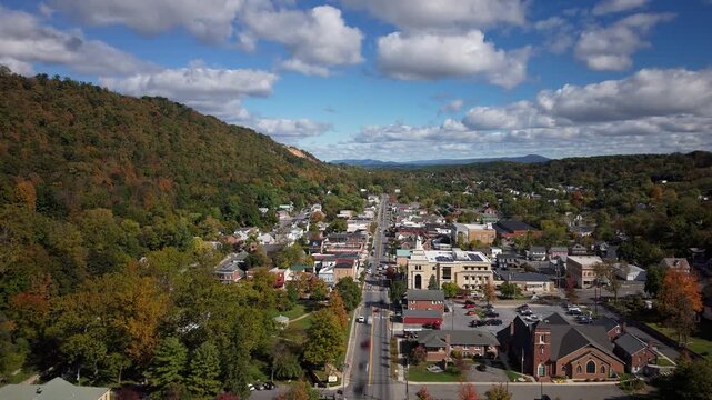 Cars and clouds race over the autumn-colored town of Bath in Berkeley Springs, West Virginia, beneath a bright blue sky.