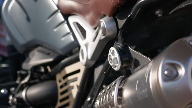 Close-up of a matte grey motorcycle tank, frame bolts, footrest bracket and twin exhaust mufflers near the rear tyre, French Riviera, France.