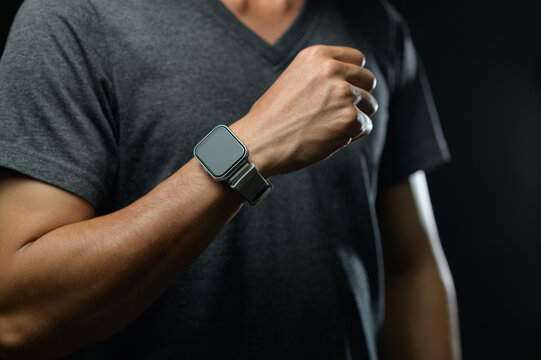 Male Athlete Wearing Fitness Tracker on Wrist in Dark Sports Environment