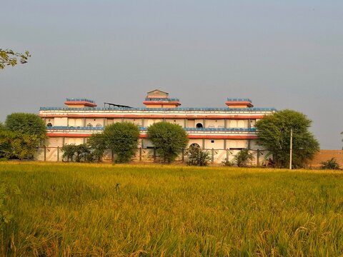 Traditional multi-story building with red-orange roofing amid dry