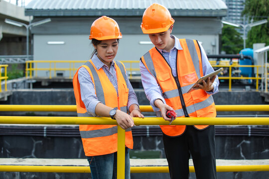 Two young engineers checking water quality after going through program wastewater treatment process program in environment industry concept.