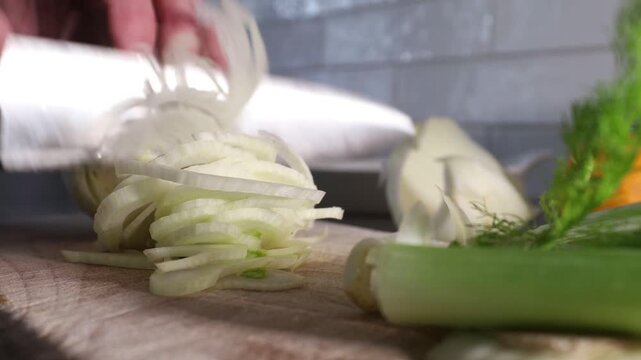 Stockholm, Sweden A cook finely slices a fennel bulb on a wooden board to make a salad. 