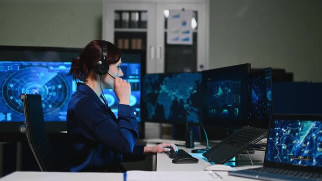 Female cybersecurity analyst working in a futuristic command center. She uses interactive screens and a headset to manage global networks.