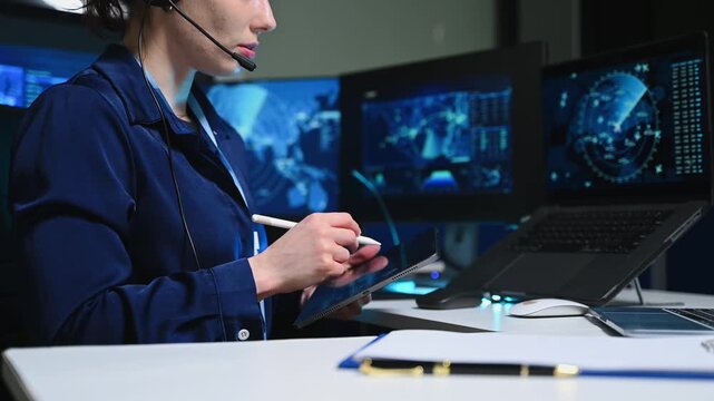 Female air traffic controller operates keyboard and monitors radar screen in navigation control center room.