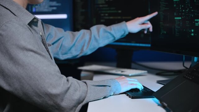Programmer using stylus and laptop to write code at night. Coding workspace with tablet, monitor, and dark theme