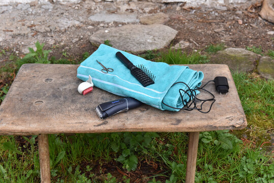 Grooming tools and turquoise towel on rustic wooden stool outdoors