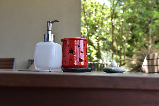 Soap dispenser and red tea light holder on a slatted wooden table