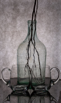 Still life with glass objects and a plant branch