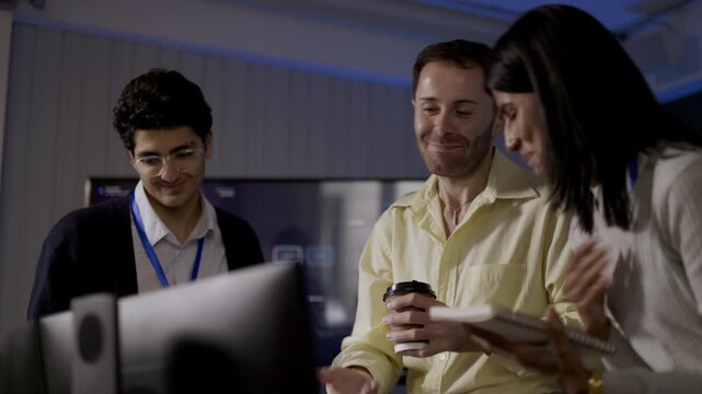 Systems Analyst listens while office colleagues review tablet information, contributing technical insight during collaborative workplace meeting, with practical colleague communication.