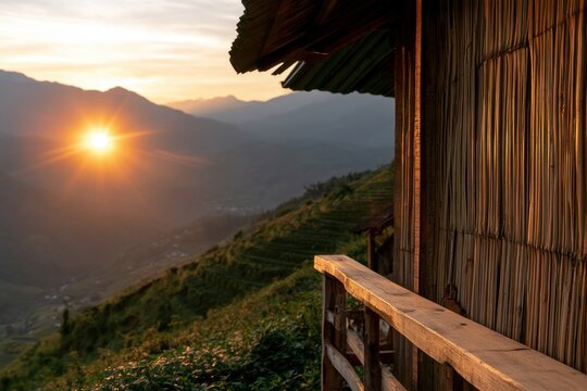 Wooden mountain shelter balcony overlooking layered hills and a glowing sunset above terraced slopes in a tranquil rural landscape