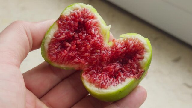 Hand Splitting Open Fresh Ripe Fig to Reveal Interior Flesh Close-Up
