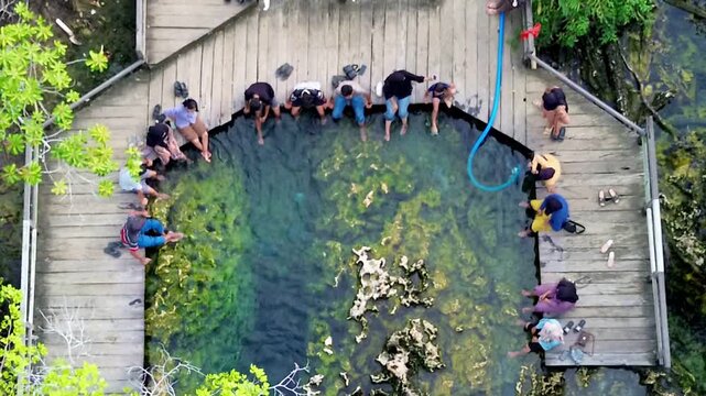Editorial aerial drone view of tourists enjoying natural salty hot spring pool at Pemapak hidden gem, Berau East Borneo.