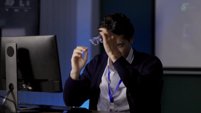 Computer Programmer holds head while leaning back from workstation, expressing frustration during demanding computer software development task, supporting challenging computer-based work.