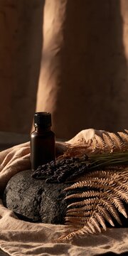 Small glass bottle with dark liquid rests on a rough stone, accented by dried foliage and textured fabric.