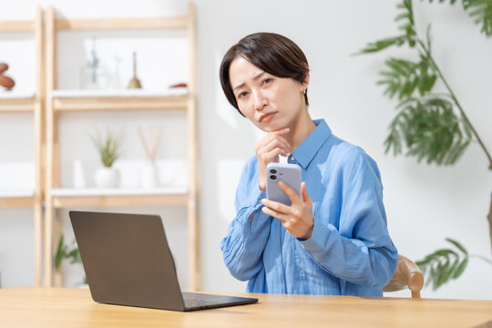 スマホを見て悩む女性