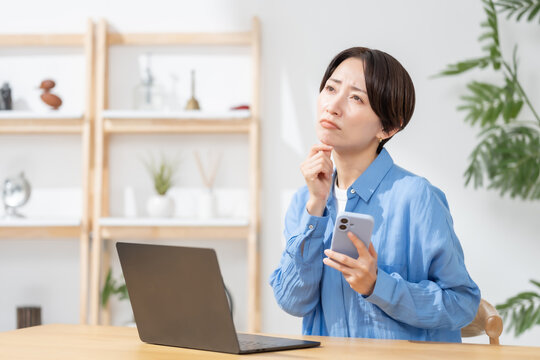 スマホを見て悩む女性